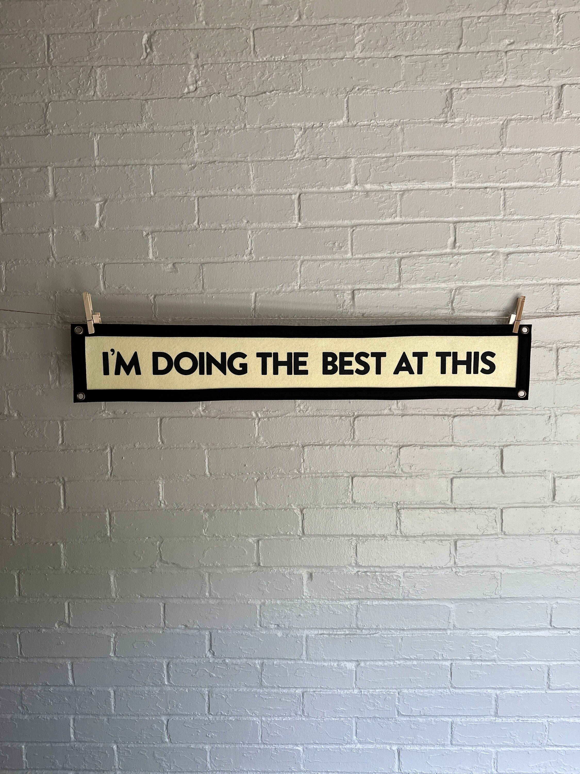 A cream banner with black trim and lettering that reads "I'm doing the best at this"