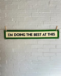 A cream banner with green trim and black lettering that reads "I'm doing the best at this"