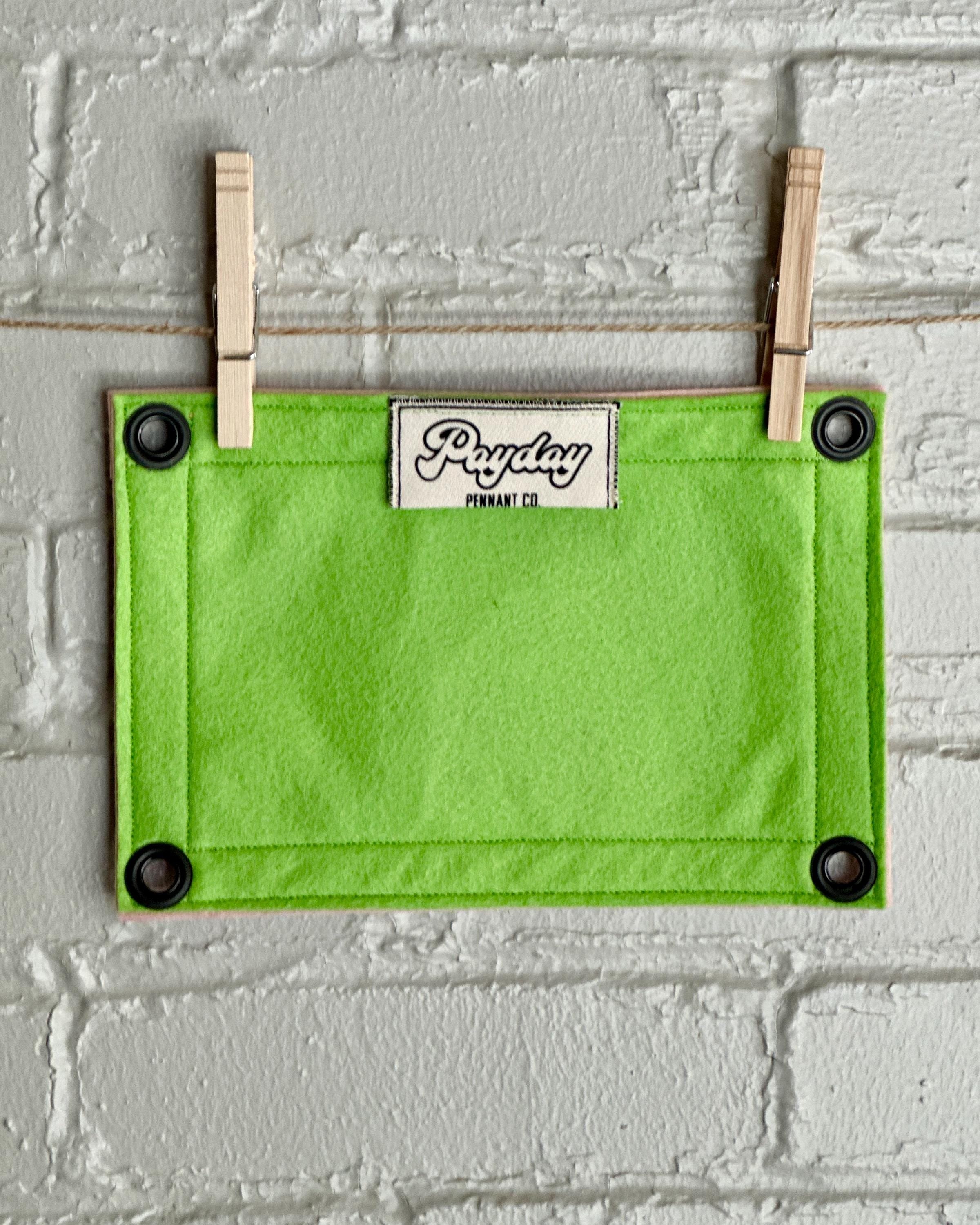Back of a bright green felt banner with light pink trim, and black lettering that reads "Bird up!"