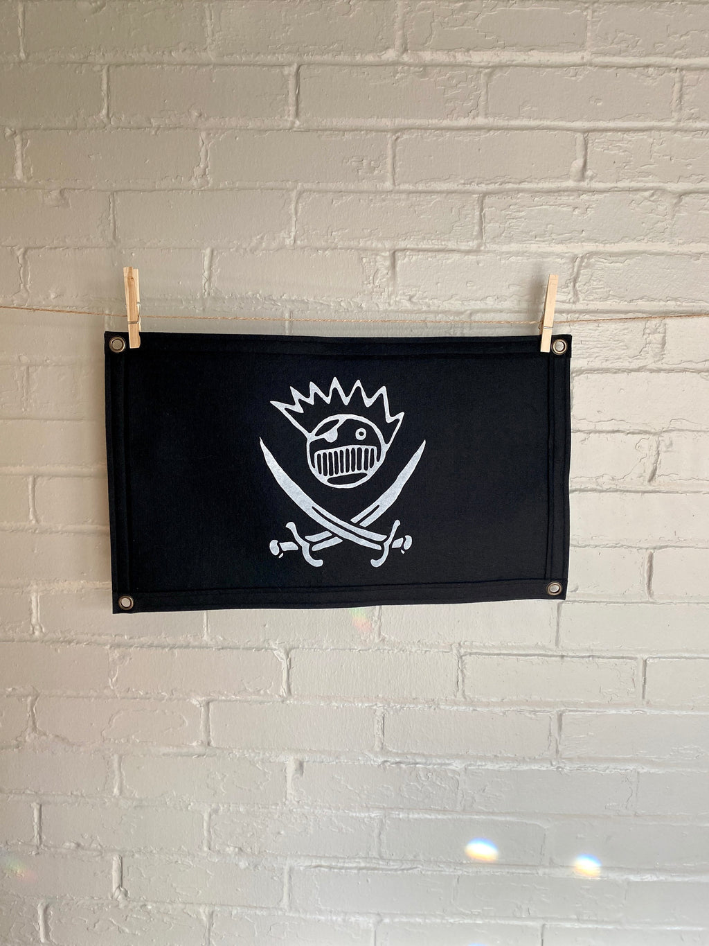 A large black felt banner with a jolly roger boognish design printed in white ink