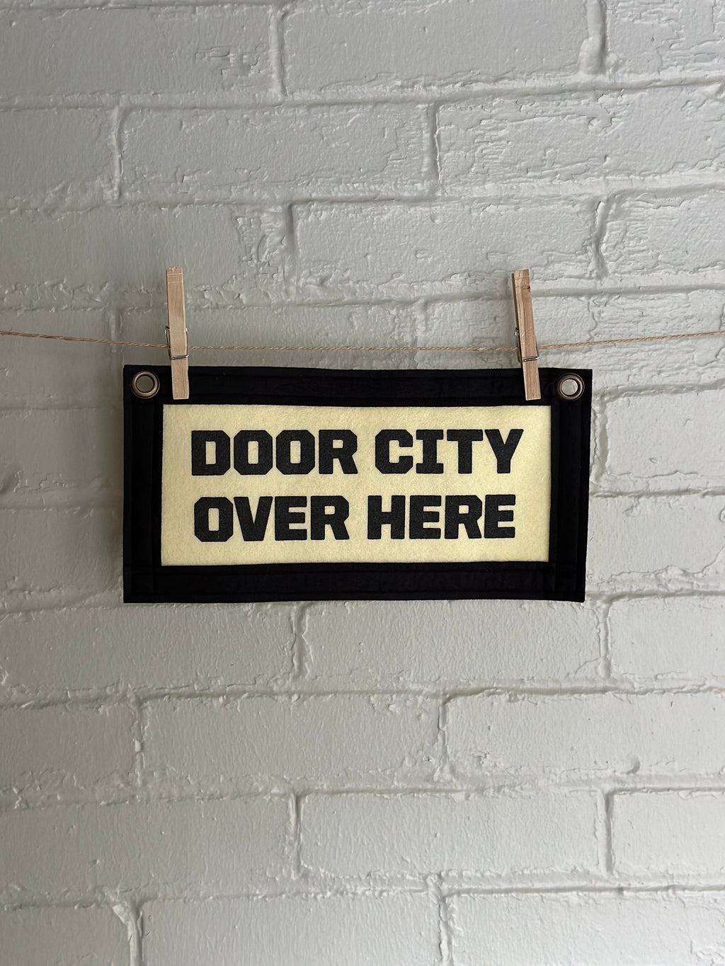Cream banner with black felt trim and lettering that reads "door city over here"
