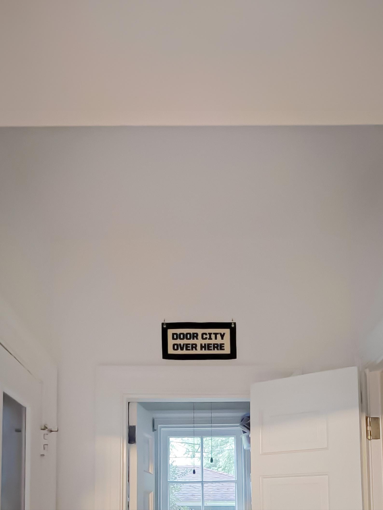 A black felt "door city" banner hanging in a home near many doorways