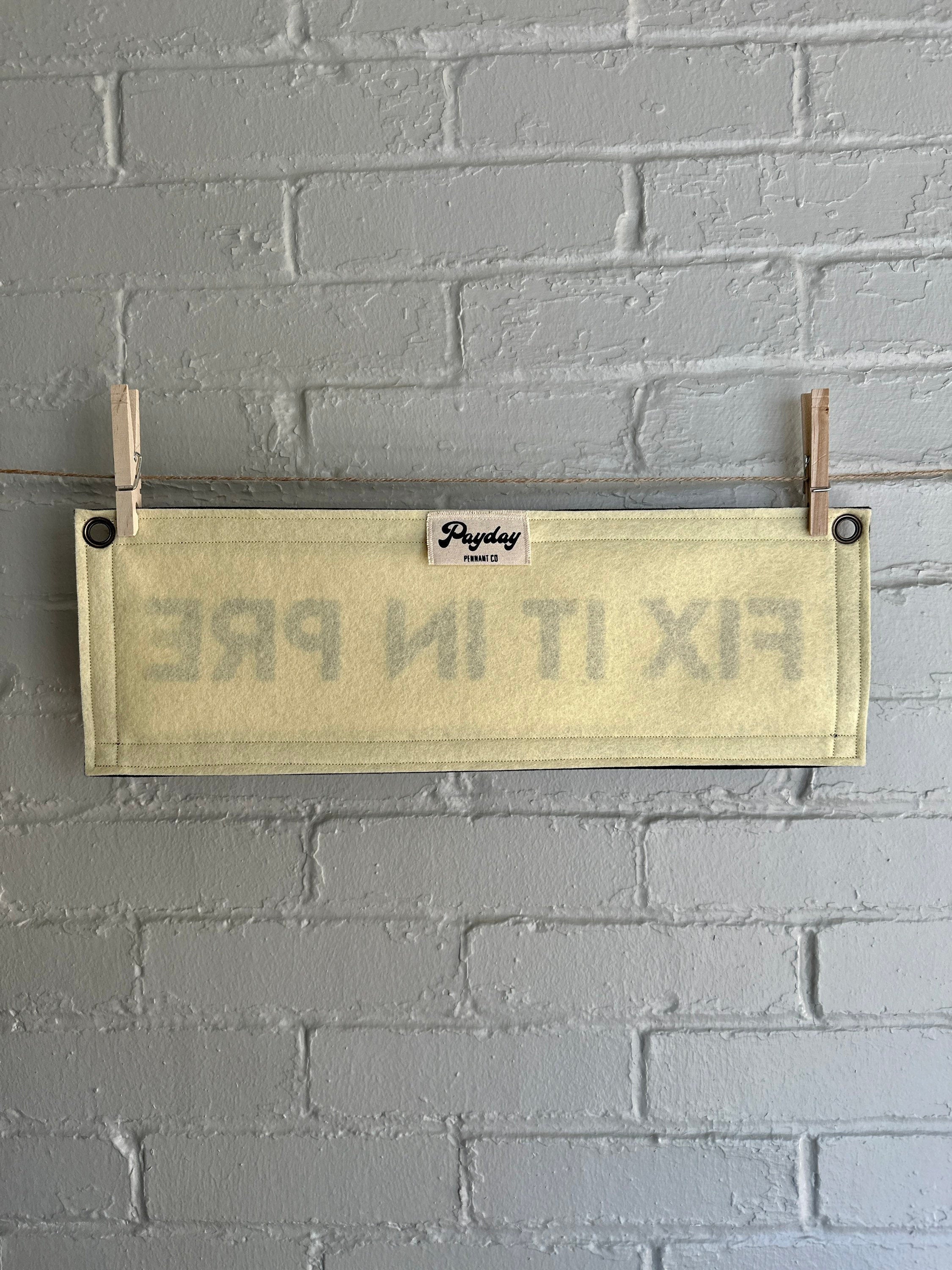 The back of a cream banner with black trim and lettering that reads "Fix it in Pre"