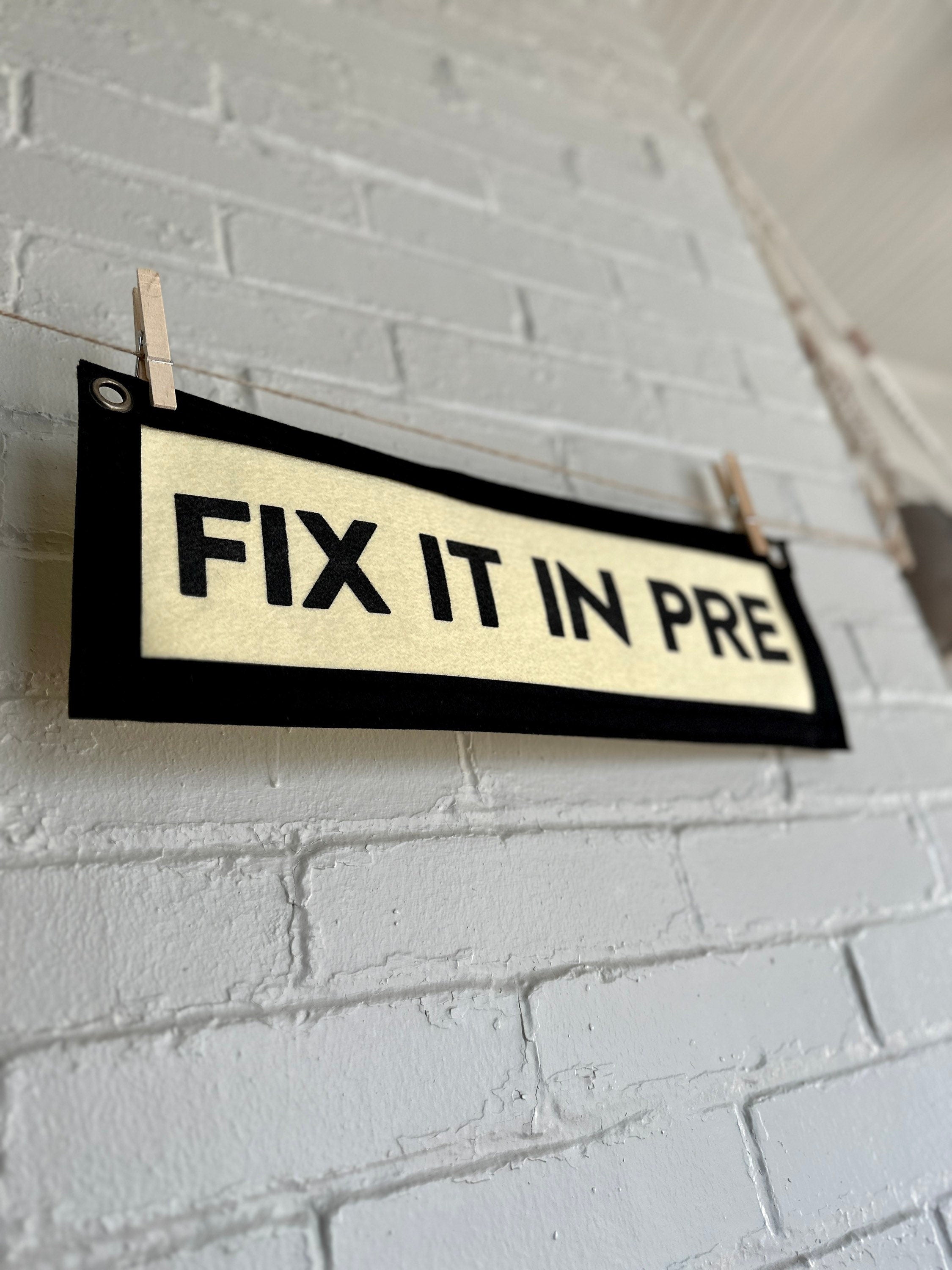 The side of a cream banner with black trim and lettering that reads "Fix it in Pre"