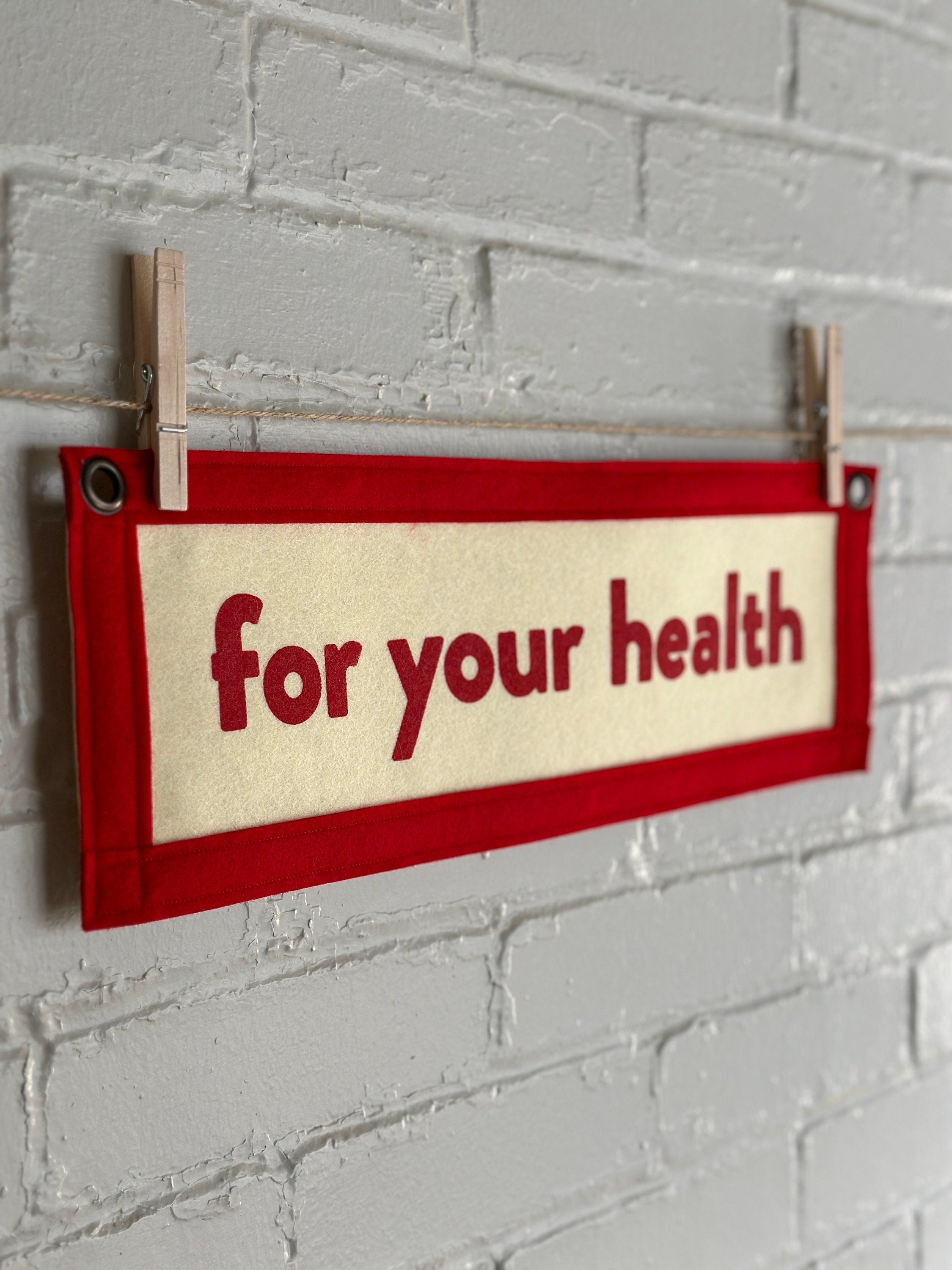 Side view of a cream banner with red felt trim and red lettering that reads "for your health"