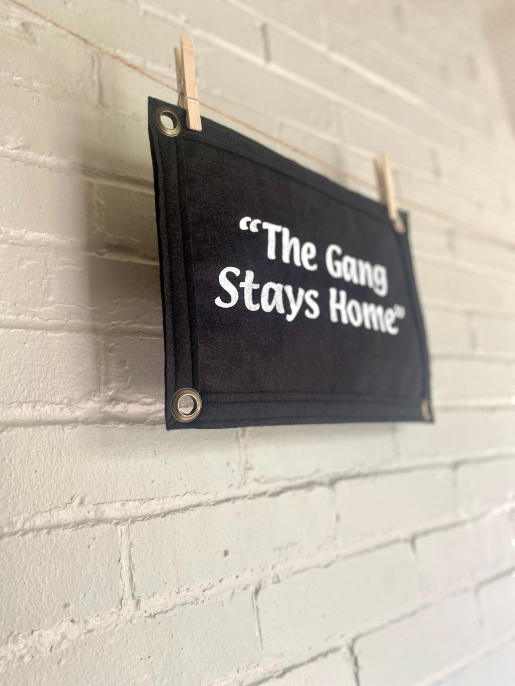 Side view of a black banner with black felt trim and white lettering that reads "the gang stays home"