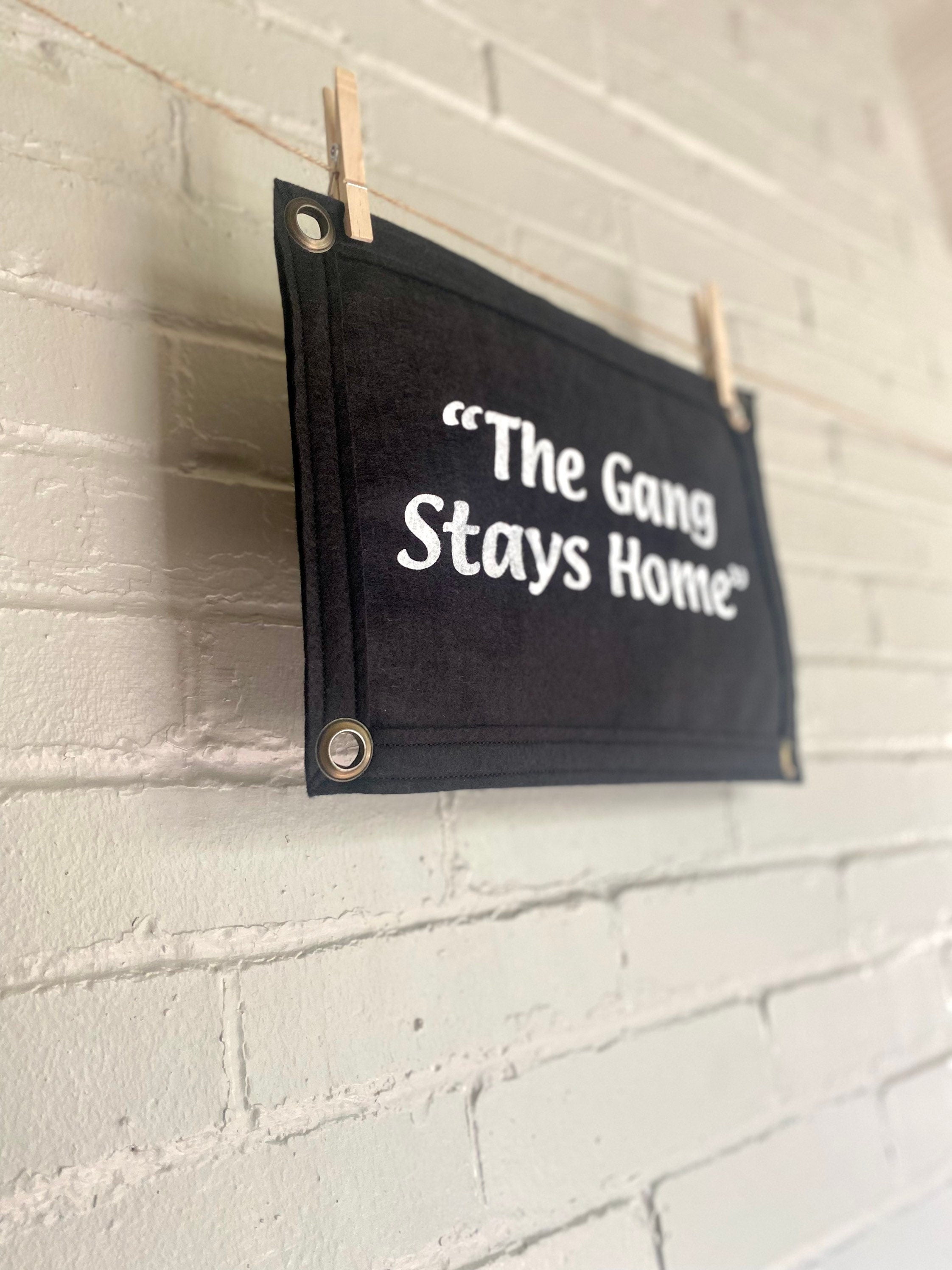 Side view of a black banner with black felt trim and white lettering that reads "the gang stays home"