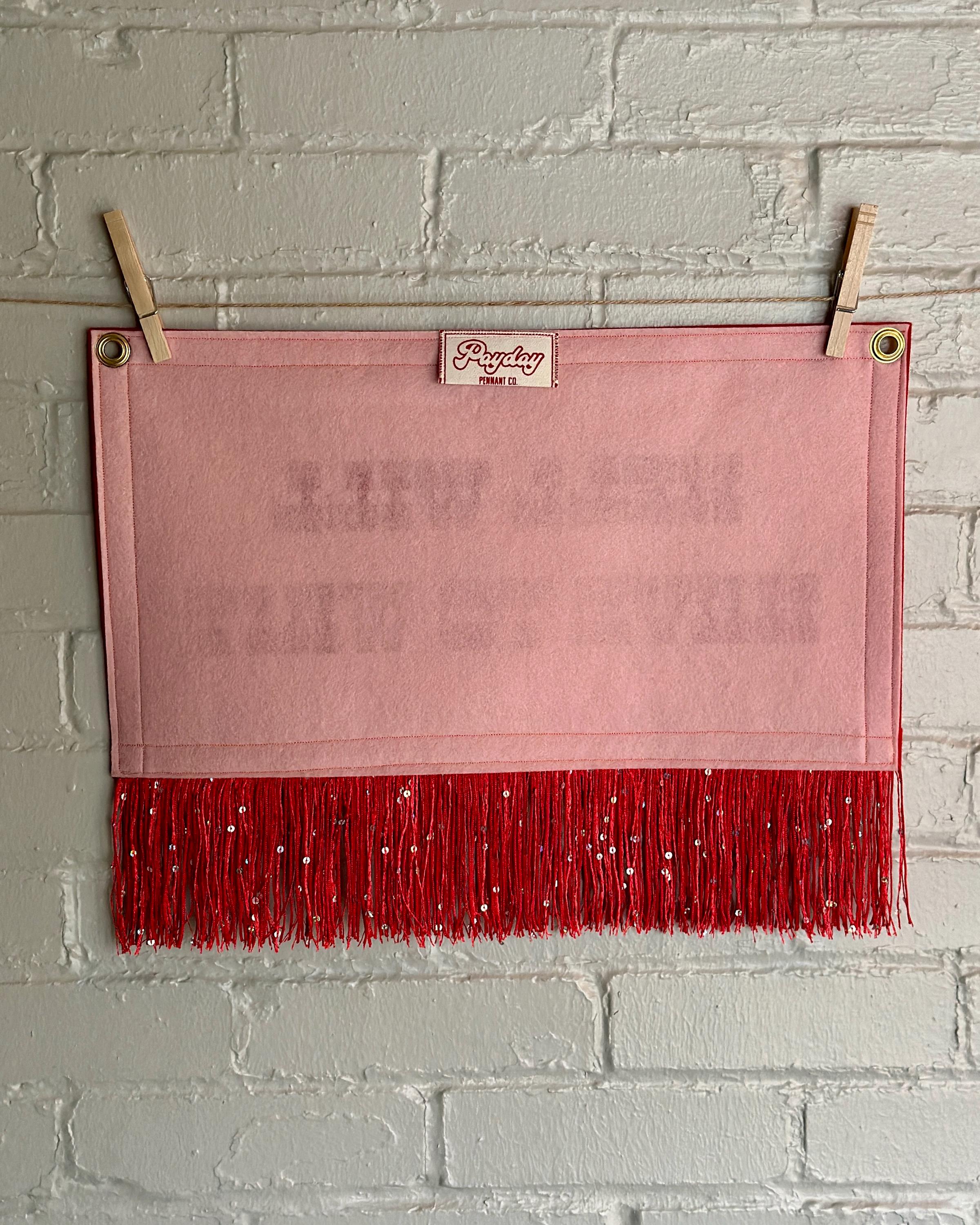 Back of a cream felt banner with red trim, long red sequin fringe, and red lettering reading "Hell will have to wait"
