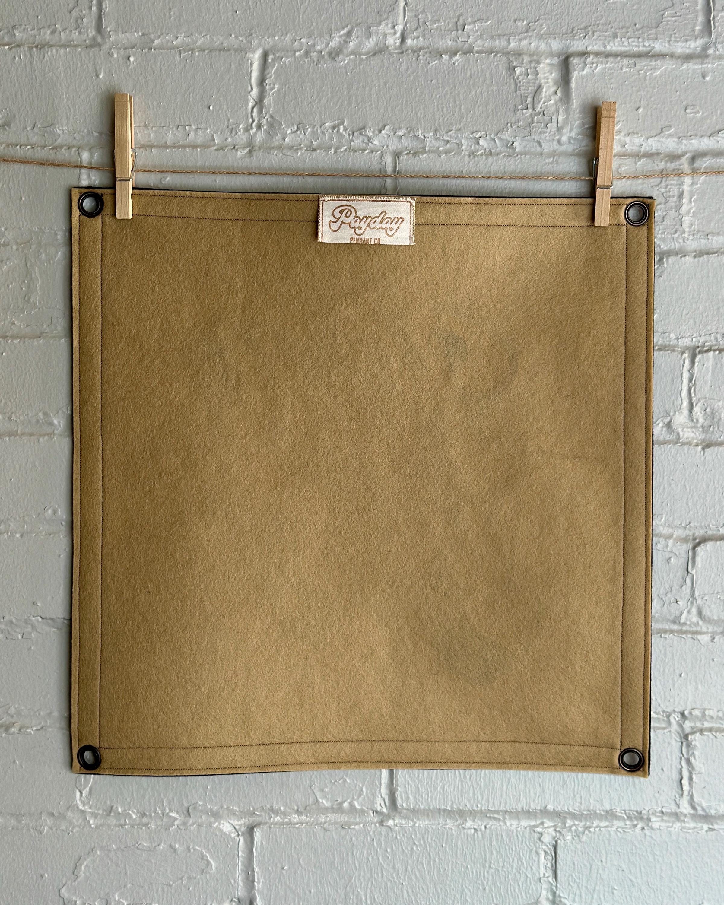 Back of a light brown banner with black trim and a large stylized vintage lettering in black and cream ink that reads "Hell yes"