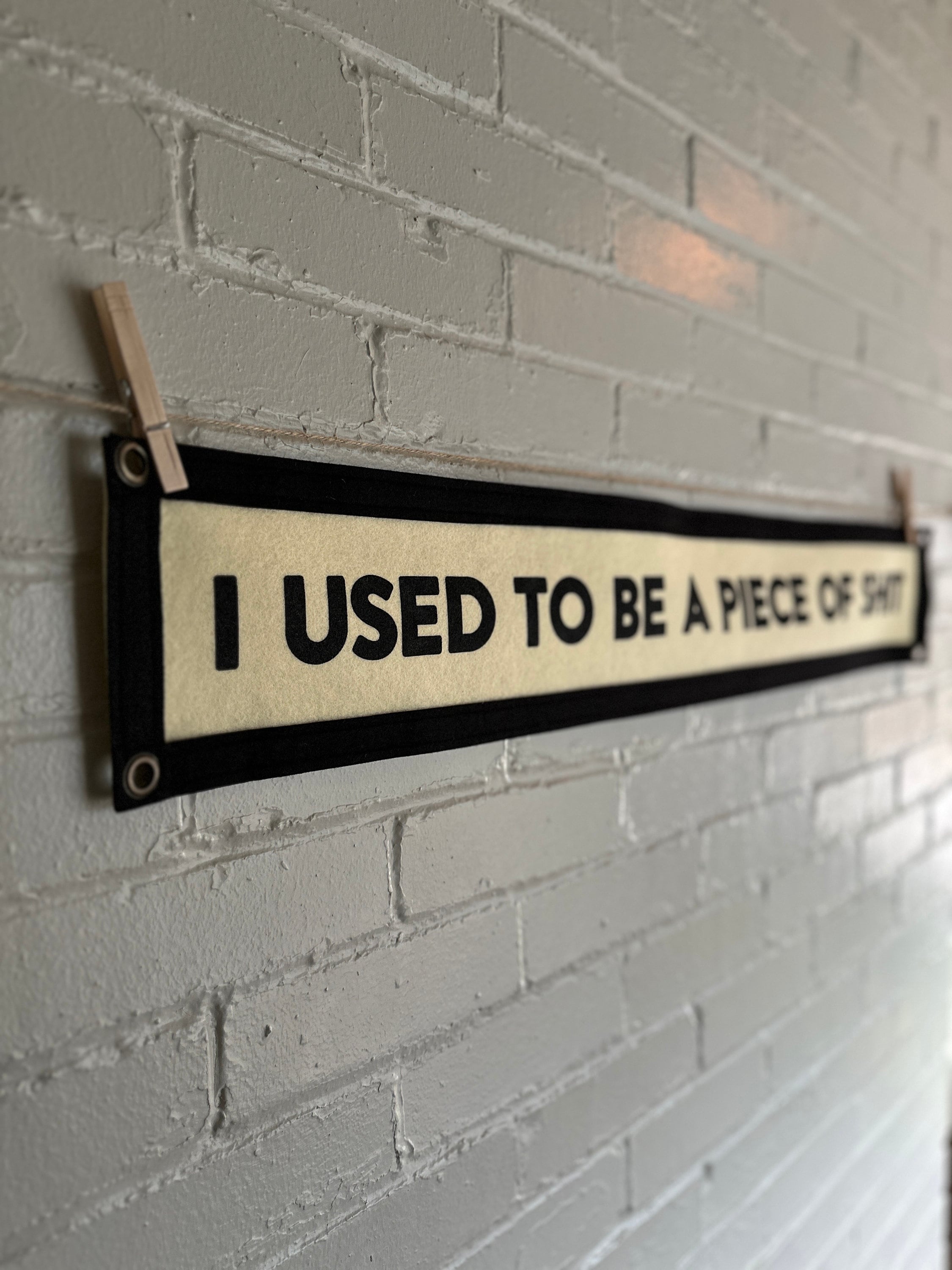 Side view of a cream banner with black trim and lettering that reads "I used to be a piece of shit"