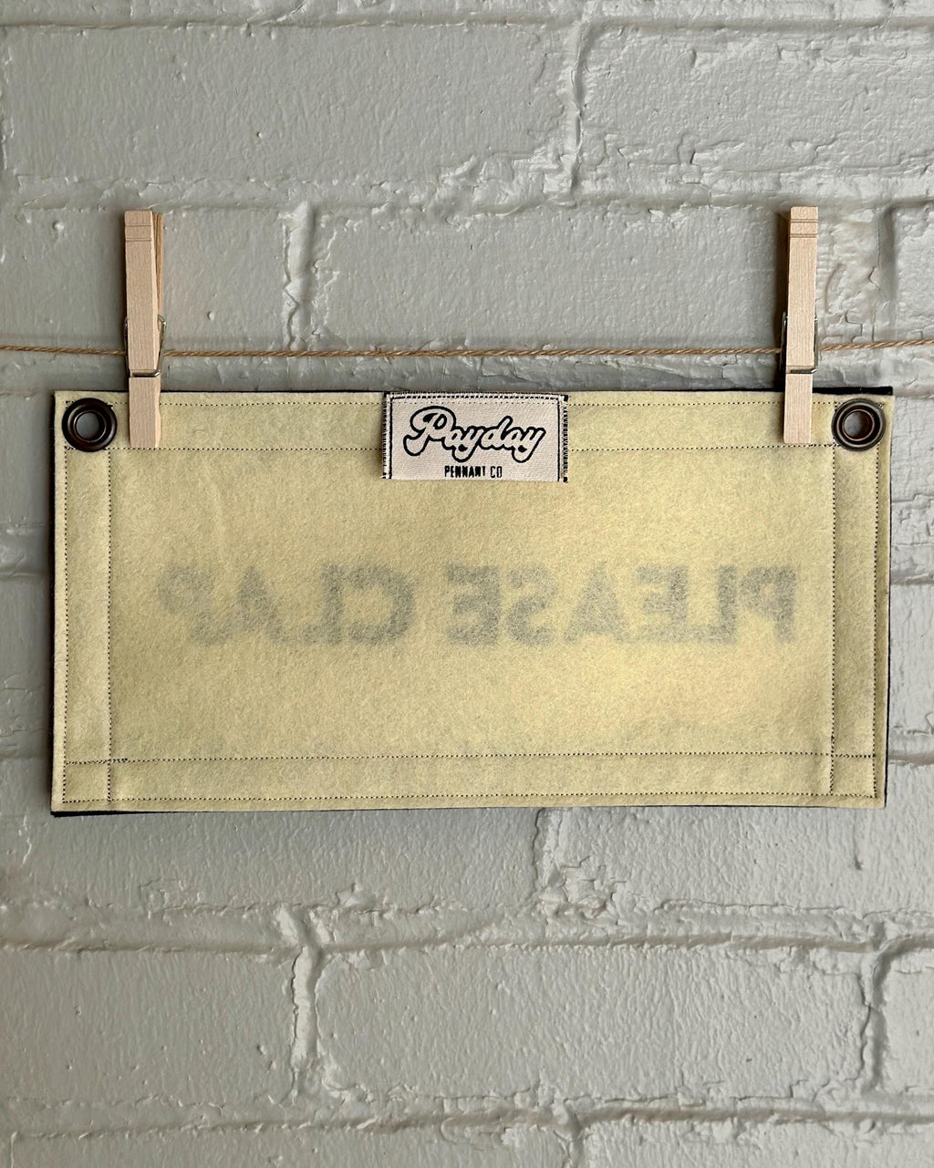 Back of a cream felt banner with black trim and lettering that reads "PLEASE CLAP"