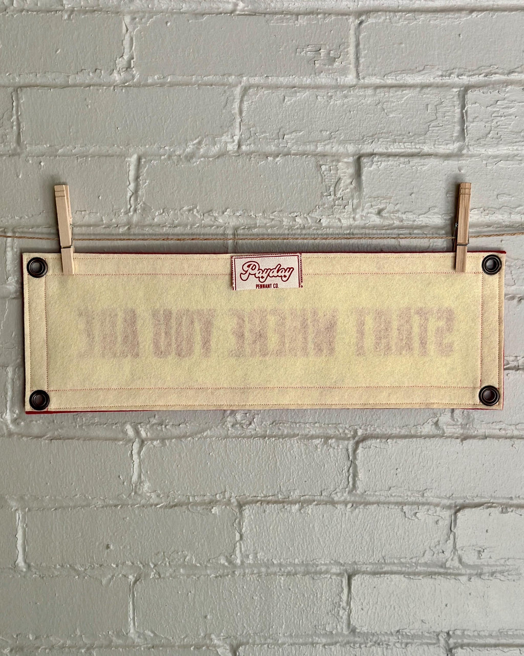Back of a cream felt banner with red trim and lettering that reads "Start where you are"
