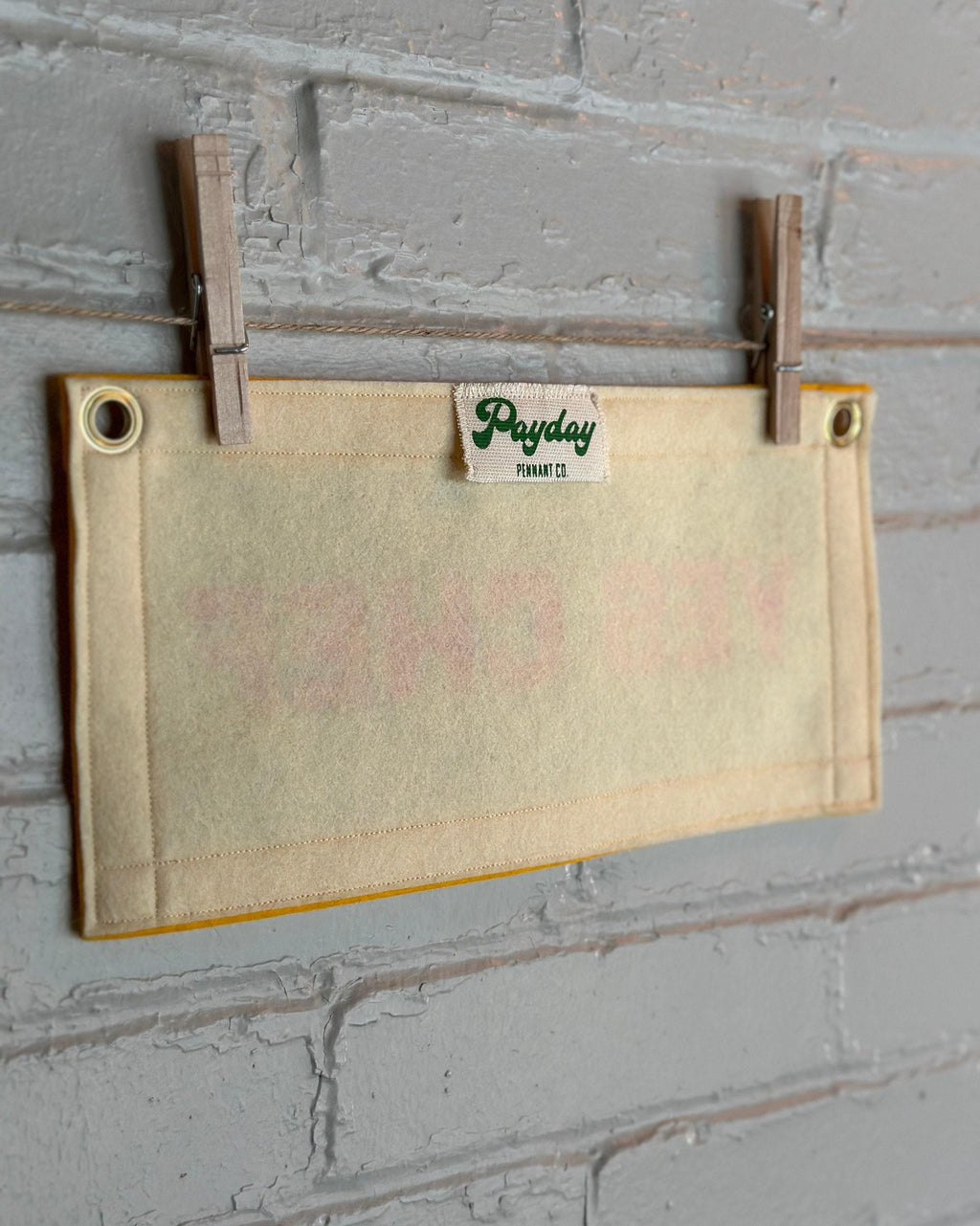 Back view of a cream felt banner with yellow trim and pink print reading "YES CHEF"