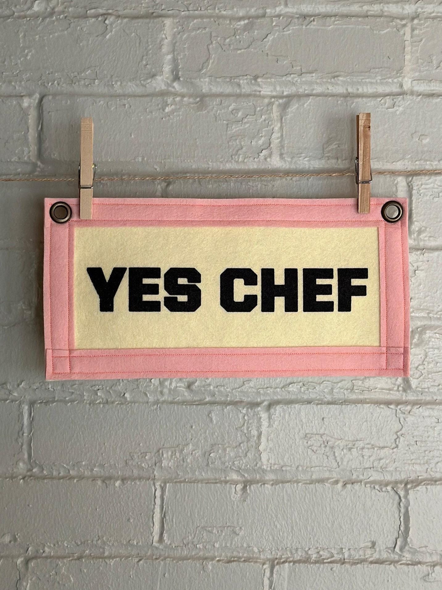 A cream felt banner with pink trim and black print reading "YES CHEF"