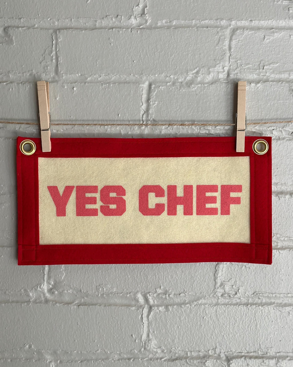A cream felt banner with red trim and pink print reading "YES CHEF"