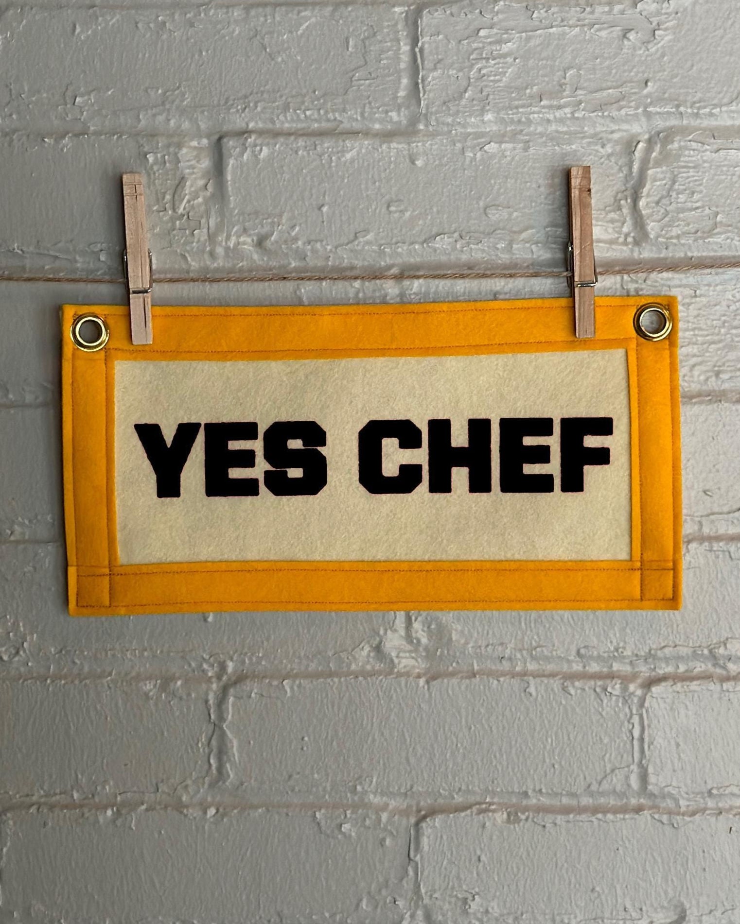 A cream felt banner with yellow trim and black print reading "YES CHEF"