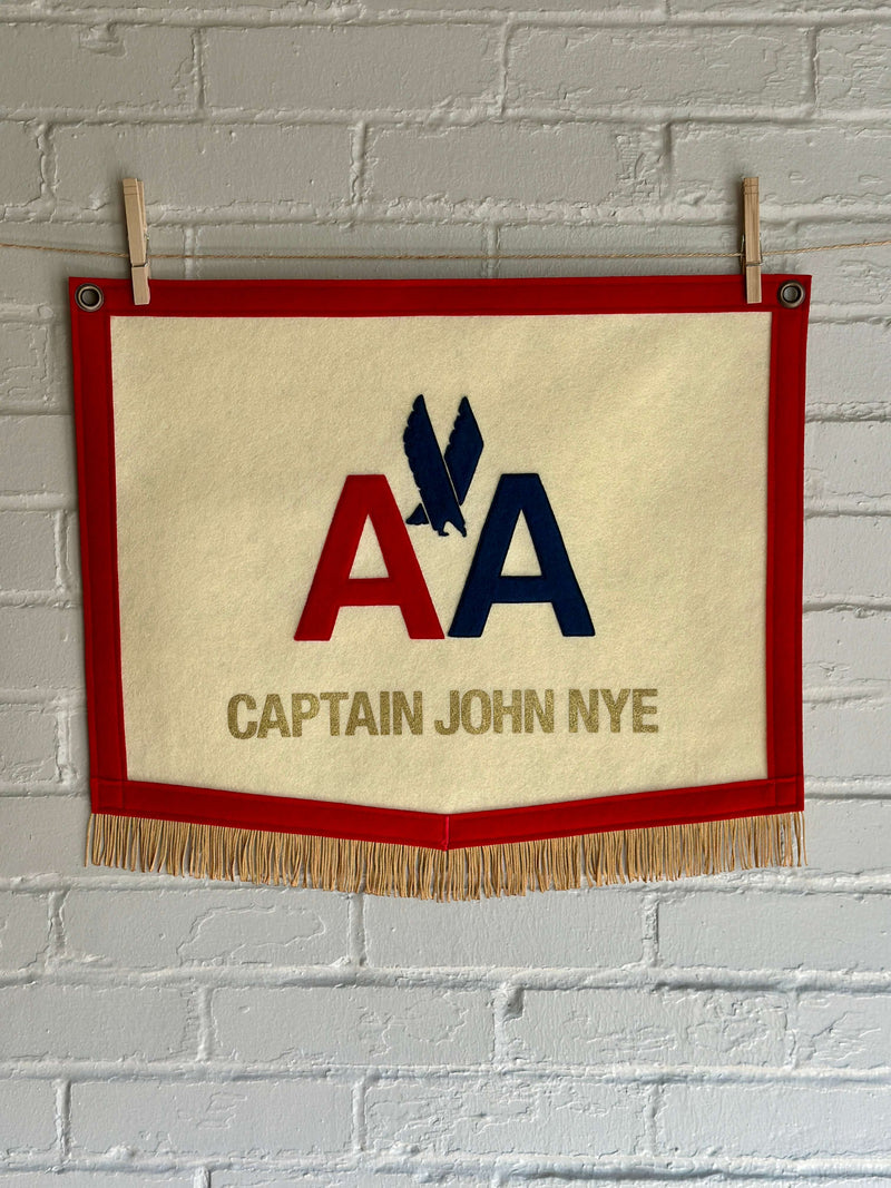 A custom felt banner with American Airlines logo and CAPTAIN JOHN NYE printed on it
