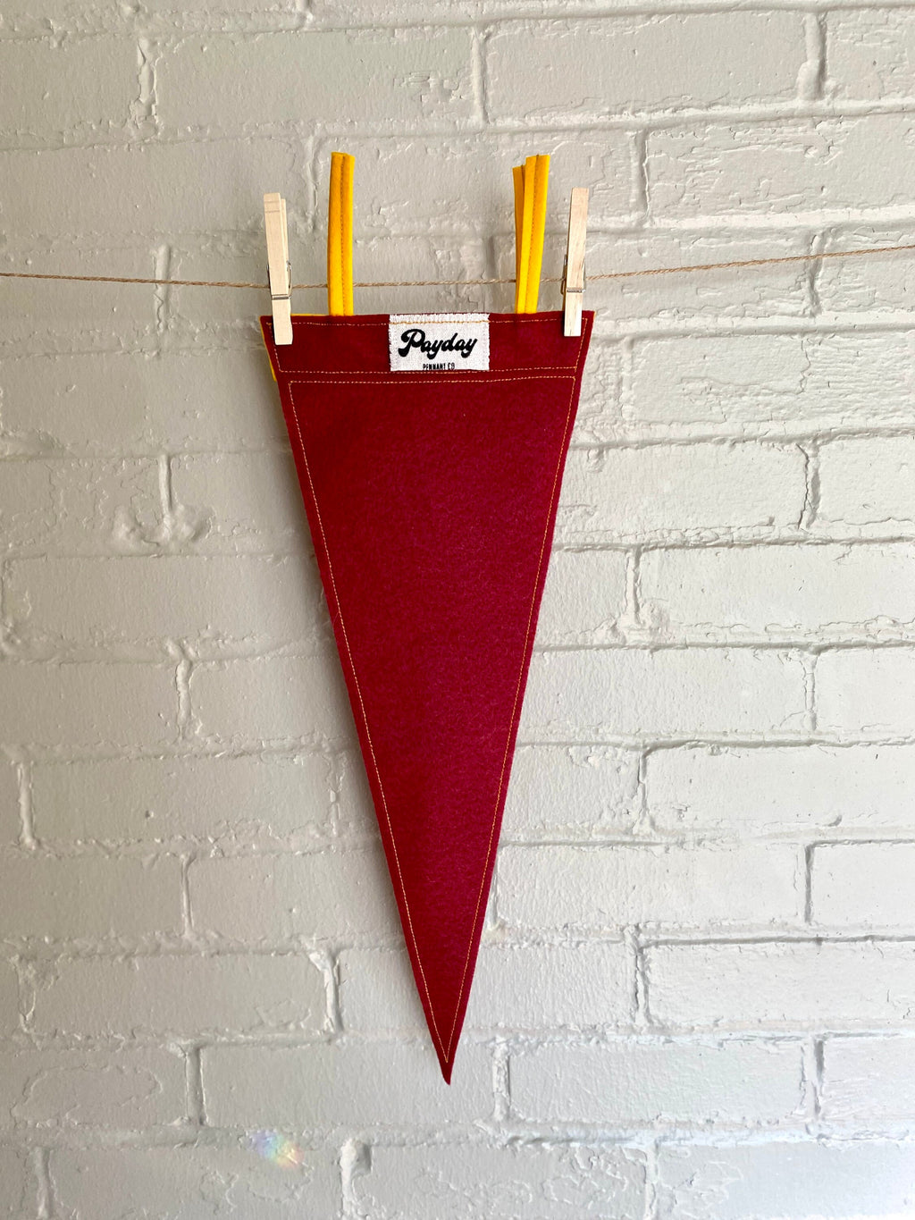 The back of a burgundy pennant with yellow felt trim and the Guild of Calamitous Intent logo printed in gold