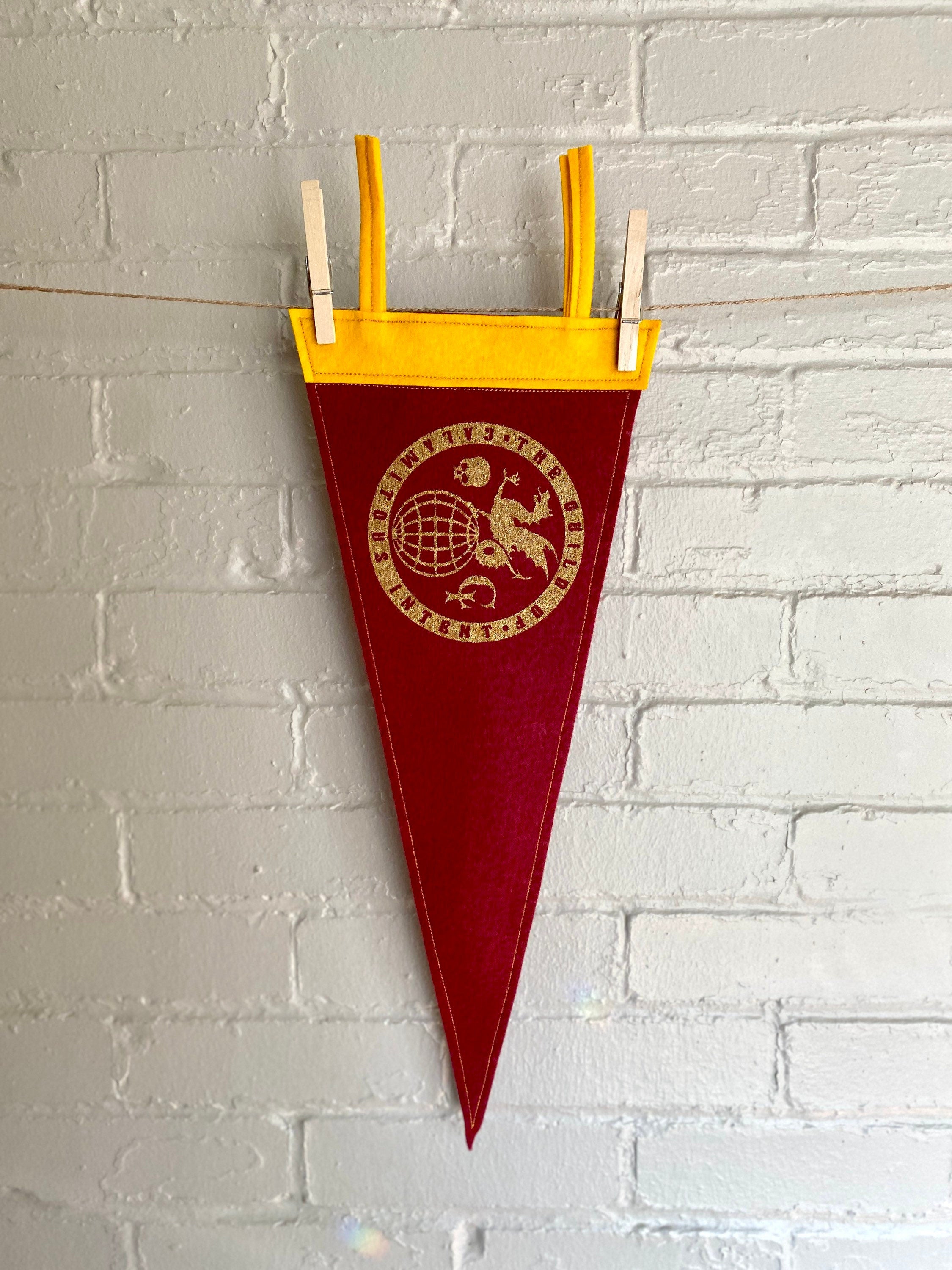 A burgundy pennant with yellow felt trim and the Guild of Calamitous Intent logo printed in gold