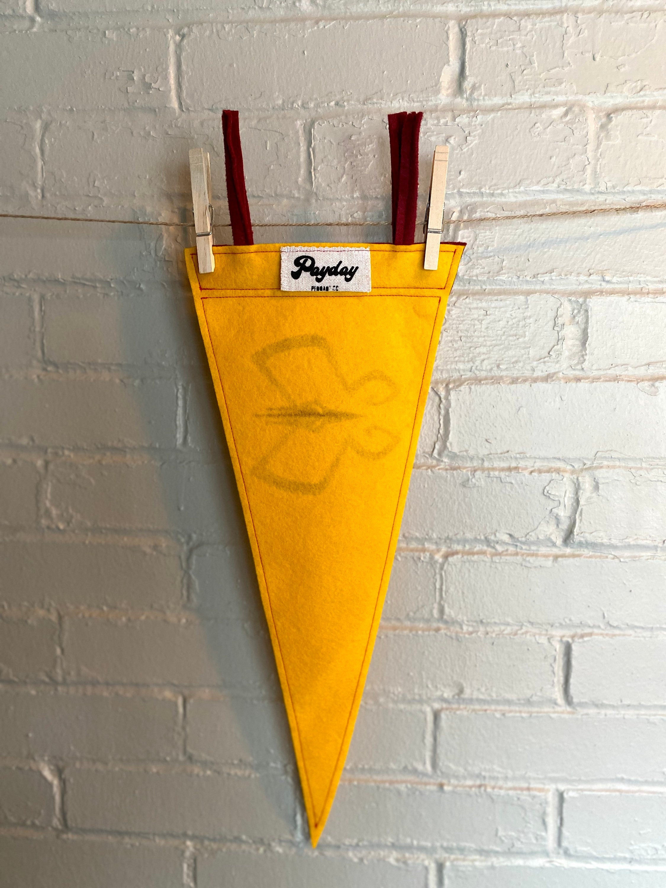 Back of a yellow pennant with burgundy trim and the Monarch's insignia from the Venture Bros printed in burgundy ink