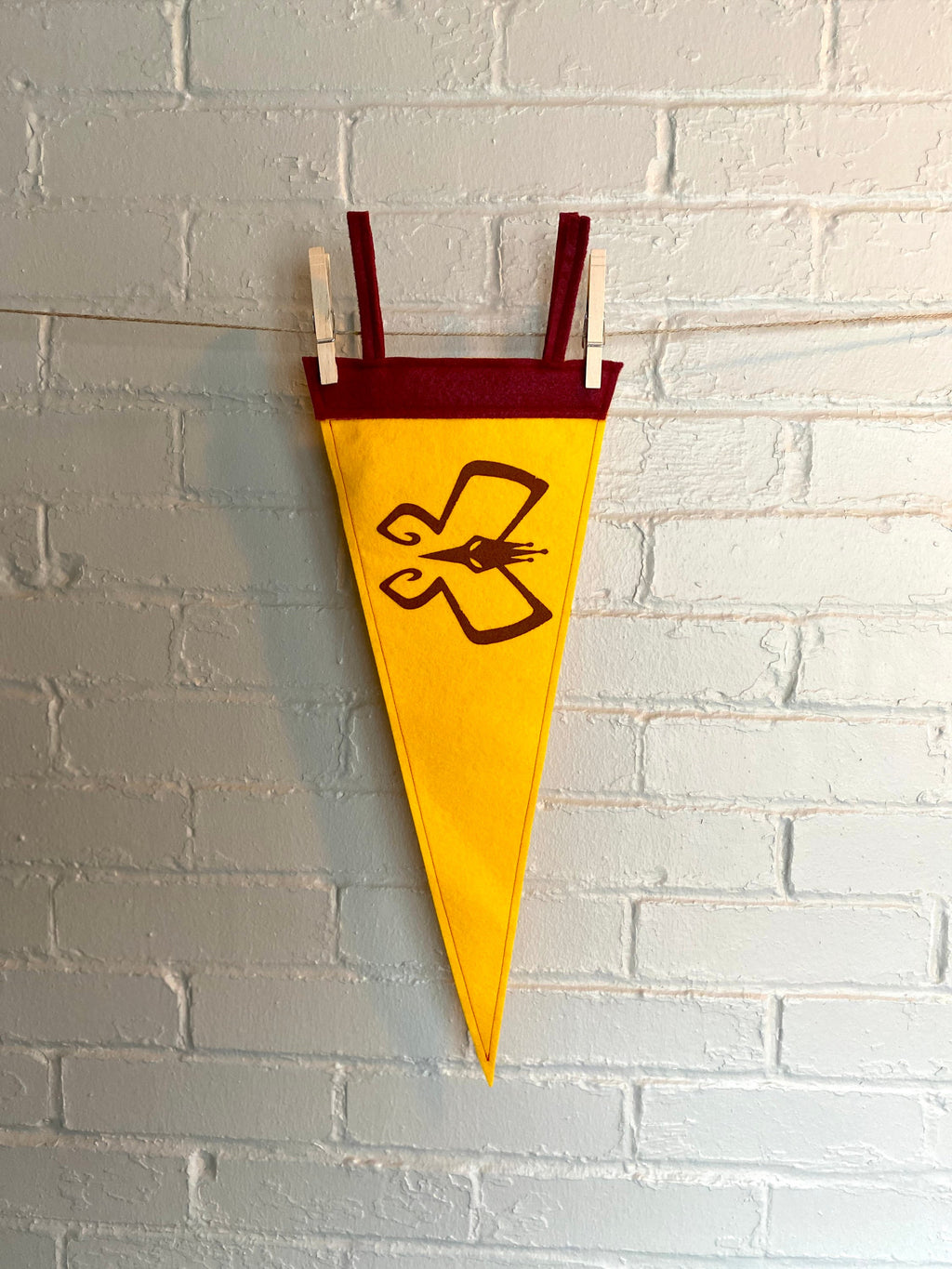 Yellow pennant with burgundy trim and the Monarch's insignia from the Venture Bros printed in burgundy ink